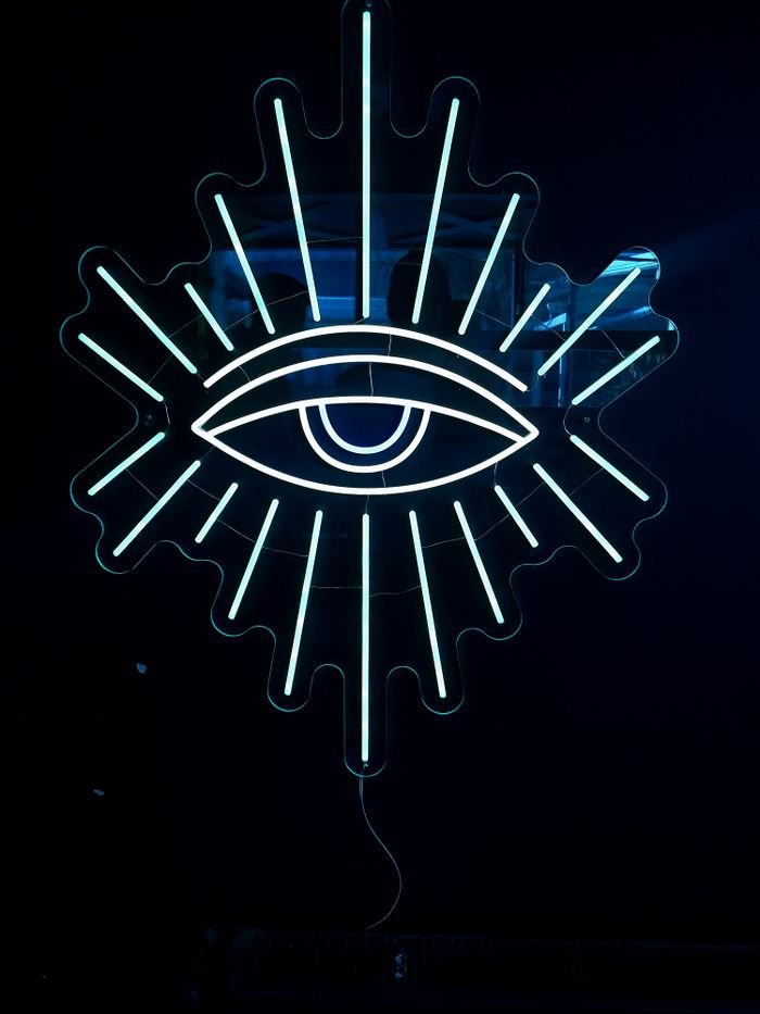 Striking neon eye with radiating lines on a dark backdrop, perfect for modern design projects.